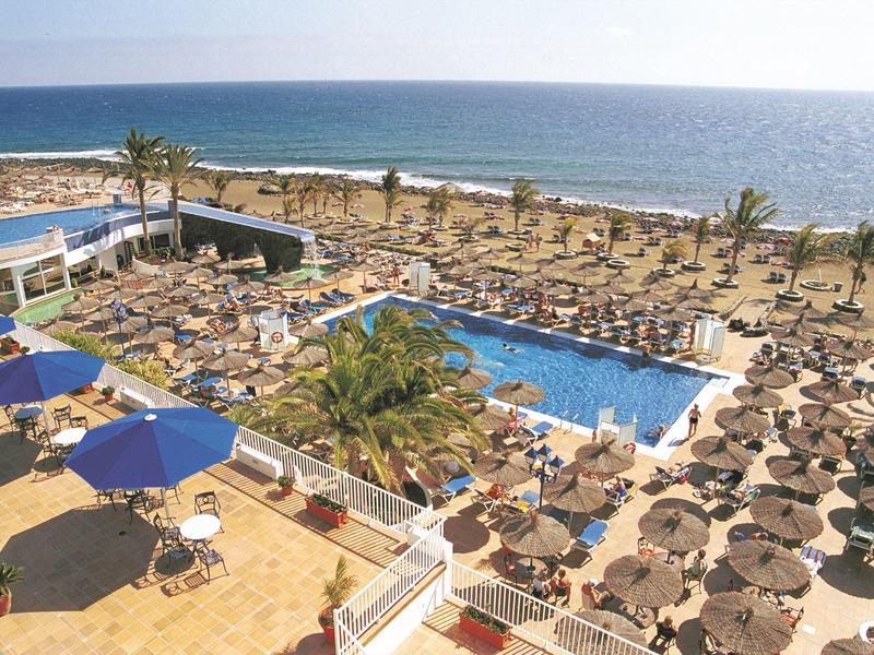 Grande piscina dell'hotel con ombrelloni e lettini vicino al mare.