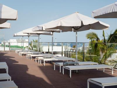 Lettini prendisole sotto ombrelloni su una terrazza dell'hotel con vista sull'oceano in una giornata di sole.