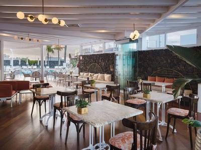 Ristorante d'hotel moderno con tavoli e sedie eleganti, luce naturale da grandi finestre.