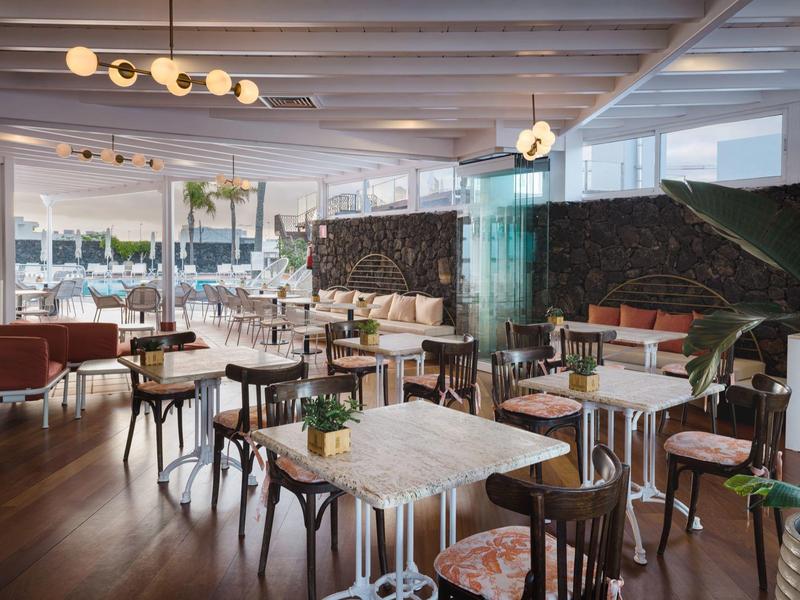 Ristorante d'hotel moderno con tavoli e sedie eleganti, luce naturale da grandi finestre.