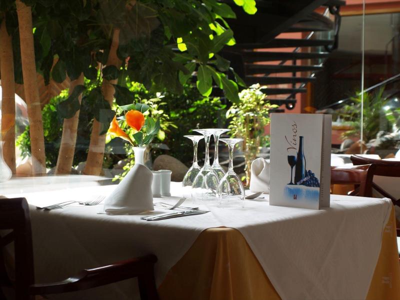 Tavolo elegantemente apparecchiato con fiori e calici in un ristorante soleggiato.