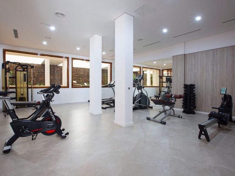 Palestra moderna con varie attrezzature sportive e grandi finestre.