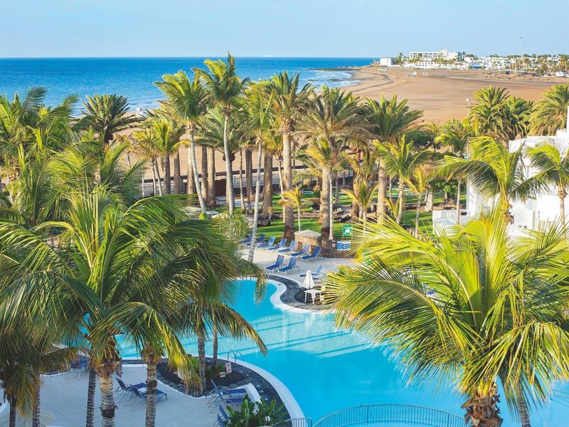 Vista di una piscina con palme e mare sullo sfondo in un luogo di vacanza.
