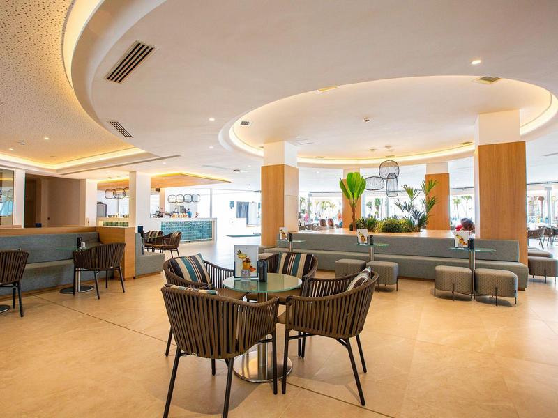 Ampia hall d'hotel moderna con gruppi di sedute eleganti e illuminazione calda.