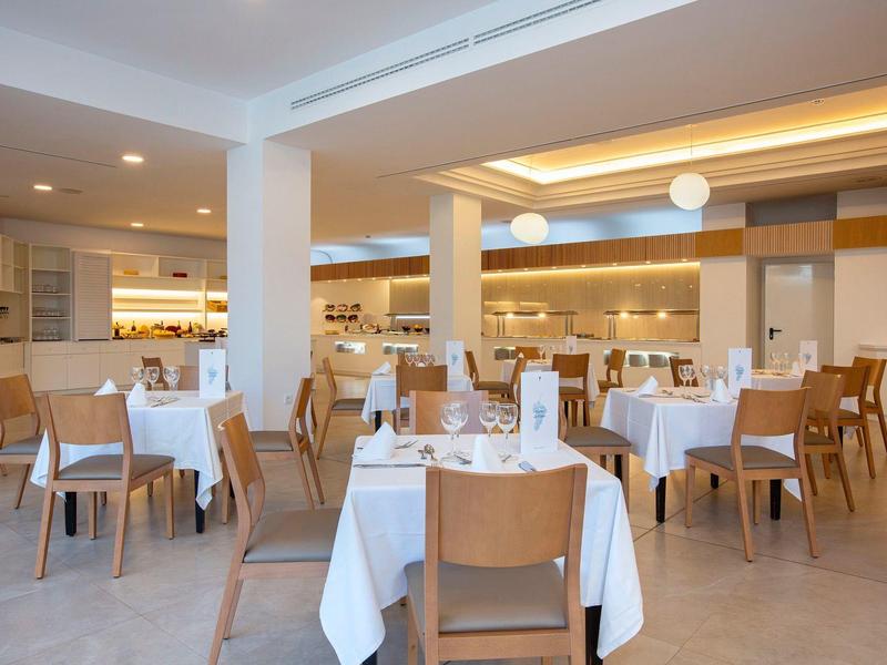 Ristorante moderno e luminoso con tavoli apparecchiati e sedie in legno.