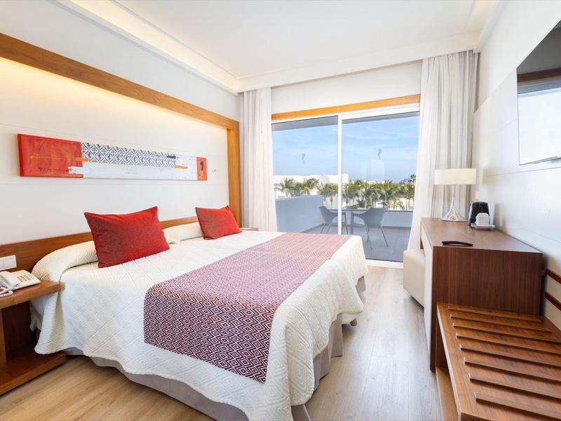 Camera d'hotel moderna con due letti, terrazza e vista mare.