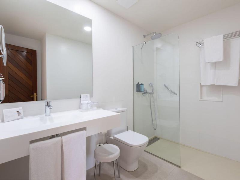 Bagno semplice con doccia, WC, lavabo e asciugamani bianchi in un hotel.