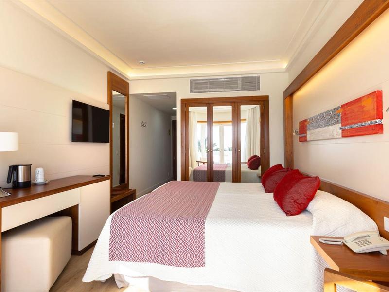 Camera d'hotel moderna con letto grande, scrivania e accesso al balcone.