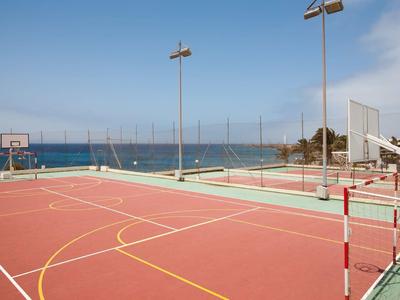 Otwarte boisko sportowe z koszem do koszykówki i siatką do siatkówki nad morzem