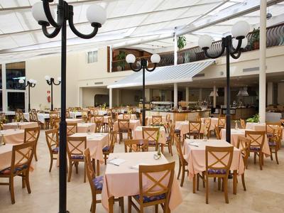Grand espace intérieur d'un restaurant lumineux avec de nombreuses tables dressées et chaises en bois.