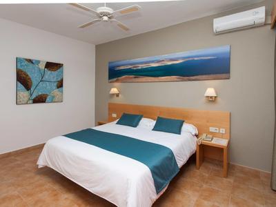 Chambre d'hôtel confortable avec grand lit, couvre-lit bleu, décoration murale et climatisation.