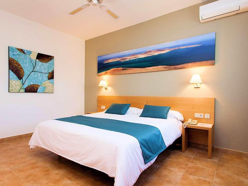 Chambre d'hôtel moderne avec lit double, lampes de chevet et œuvre d'art abstraite.