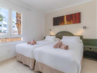 Helles Schlafzimmer mit zwei Einzelbetten, weißen Bettdecken, grünen Nachttischen und großem Fenster.