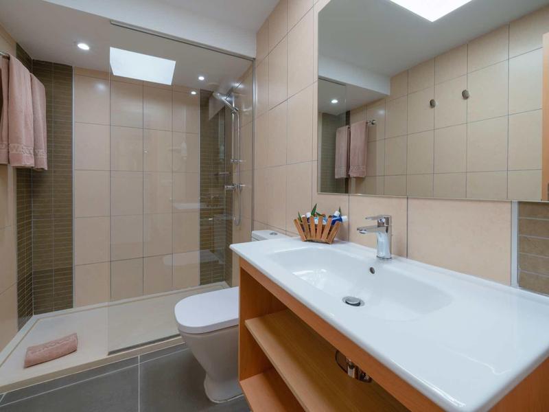 Modernes Badezimmer mit großem Waschbecken, beleuchtetem Spiegel und begehbarer Dusche.