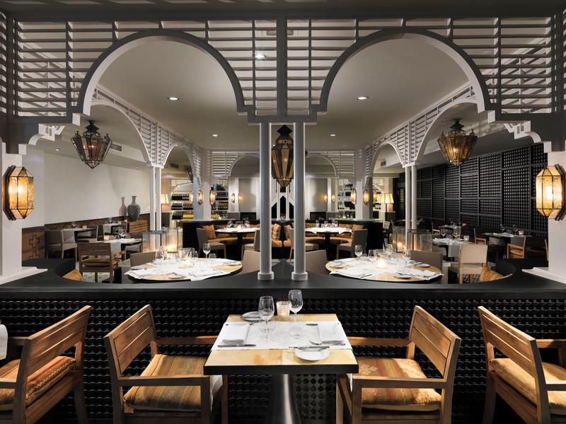 Restaurante elegante de hotel con muebles de madera, mesas blancas y luces cálidas de faroles.