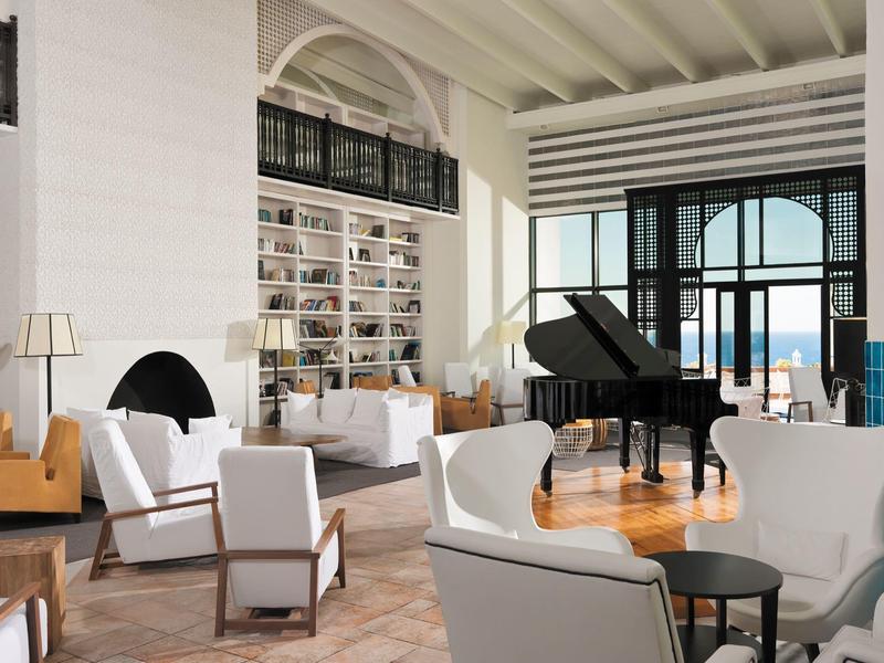 Sala de hotel moderna con sillones blancos y un piano de cola negro.