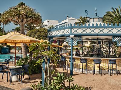 Bar en plein air avec chaises et tables à côté d'une piscine dans un complexe hôtelier tropical.