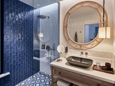 Bagno moderno con specchio ovale, lavabo nero e piastrelle blu.