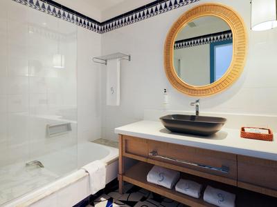 Bagno moderno con doccia in vetro, lavabo su mobile in legno e specchio rotondo.