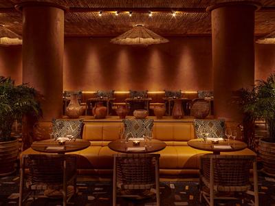 Salon d'hôtel confortable avec canapé, chaises, tables et éclairage tamisé