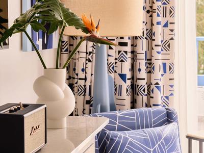 Fauteuil confortable avec rideaux à motifs et lampe décorative dans une pièce élégante.