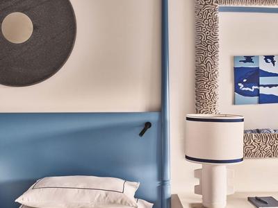 Chambre moderne avec lit simple, tête de lit bleue et décorations murales.