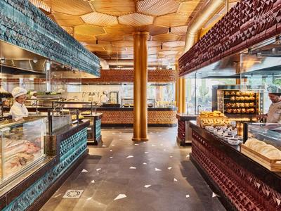 Intérieur d'une boulangerie élégante avec comptoirs éclairés et plafond en bois.