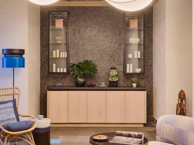 Salon élégant avec lustre moderne, sièges et buffet dans des tons neutres.