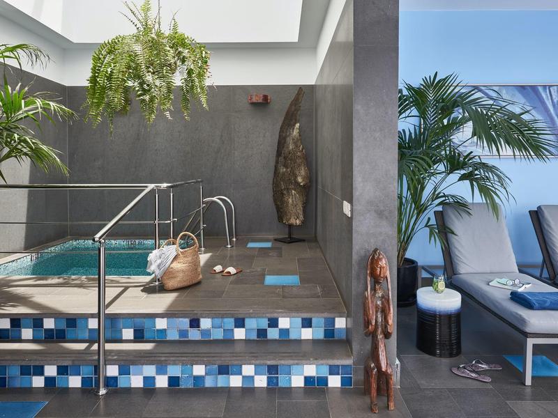 Area benessere moderna con piccola piscina, piante e lettini.