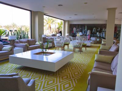 Helles Wohnzimmer mit großen Fenstern, gelbem Teppich, modernen Sofas und einem quadratischen weißen Tisch.