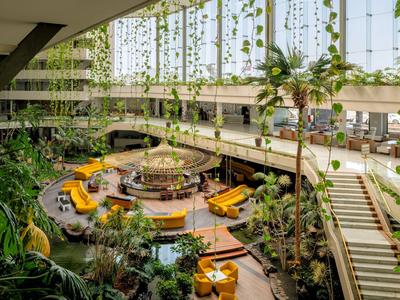 Large indoor space with tropical plants, modern seating area, and plenty of natural light.