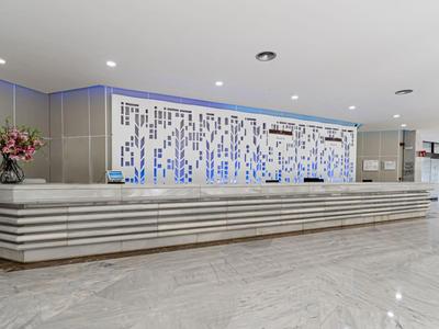 Modern hotel reception area with long counter and decorative wall behind the desk.