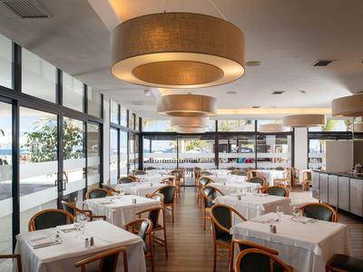 Bright restaurant with large windows, white tablecloths, and modern lamps.
