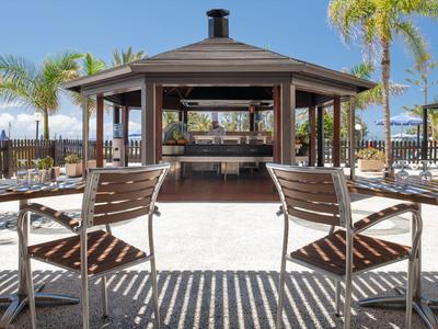 Open pavilion with seating and palm trees in a sunny outdoor hotel area.