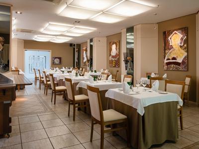 Gemütliches Restaurant mit eingedeckten Tischen, braunen Stühlen und warmen Wandfarben.