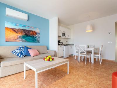 Soggiorno moderno con divano, tavolino, sala da pranzo e cucina a vista.