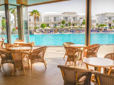 Terrazza del ristorante con tavoli e sedie di fronte a una grande piscina dell'hotel.