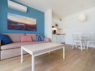 Modern eingerichtetes Wohnzimmer mit Sofa, Tisch, Essbereich und Küchenzeile.