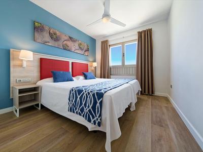 Modernes Hotelzimmer mit Doppelbett, Holzfußboden und blau-weißem Farbschema.