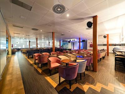 Modernes, großzügiges Restaurant mit Holzparkett, bunten Stühlen und gedämpfter Beleuchtung.