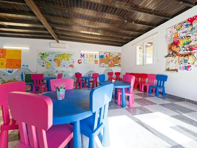 Bunt eingerichteter Kinderraum mit kindgerechten Tischen und Stühlen in einem hellen Raum.