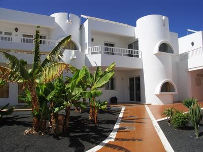 Facciata bianca di un hotel moderno con piante verdi e cielo azzurro.