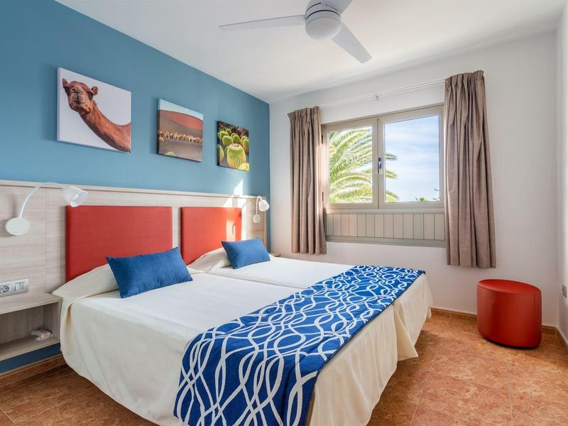 Camera d'hotel luminosa con letto doppio, decorazioni blu e bianche, finestra e tende.