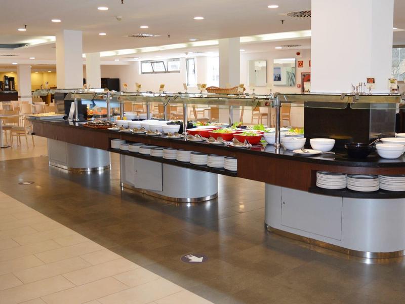 Buffet moderno con vari piatti e ciotole bianche in un ambiente luminoso.