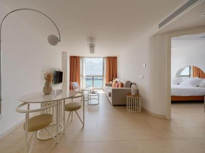 Moderner Hotelraum mit Sitzbereich, Terrasse und Blick auf das Meer.