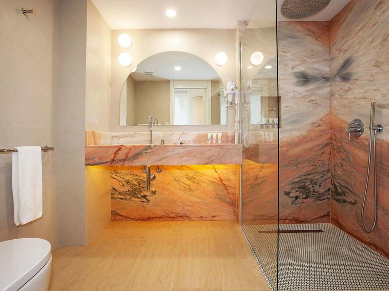 Modernes Badezimmer mit marmoriertem Waschbecken und begehbarer Dusche mit Glaswand.