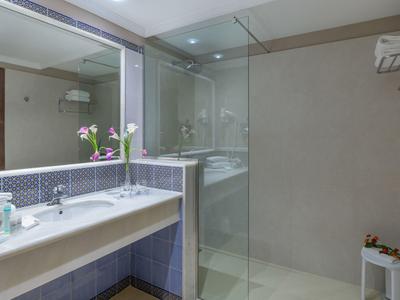 Nowoczesna łazienka z dużym lustrem, umywalką i prysznicem z przeszkloną kabiną.