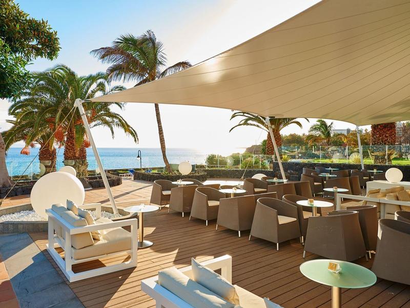 Otwarty taras z meblami wypoczynkowymi i widokiem na morze pod daszkami przeciwsłonecznymi