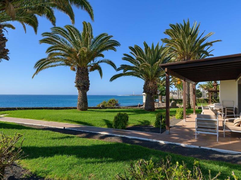 Nowoczesny teren na zewnątrz hotelu z palmami, trawiastym ogrodem i widokiem na morze.