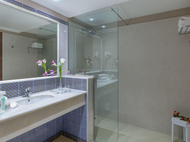 Nowoczesna łazienka z dużym lustrem, umywalką i prysznicem z przeszkloną kabiną.